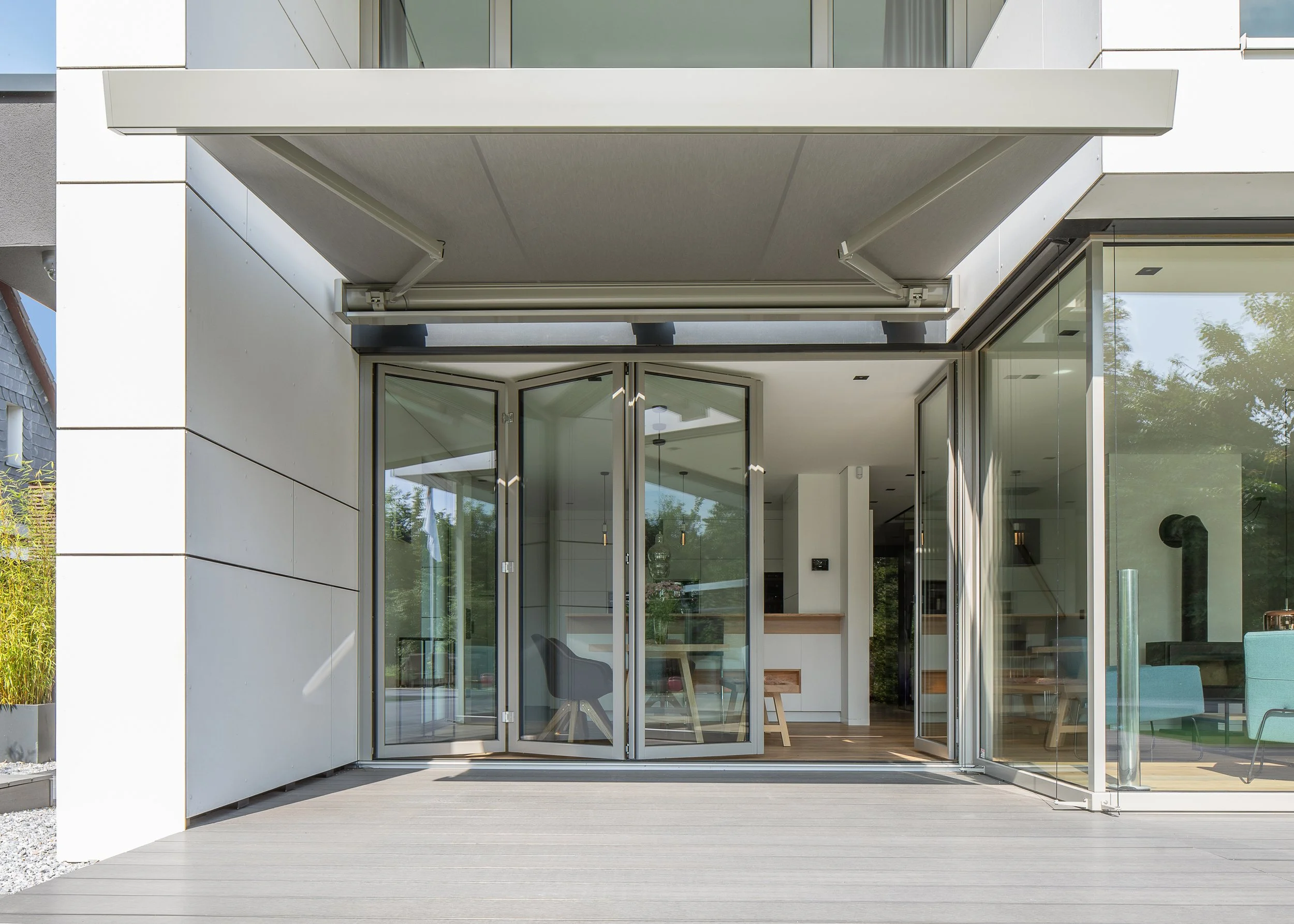 Moderne Gebäude mit großen Glasfenstern und einem offenen Balkon mit automatischer Markise.