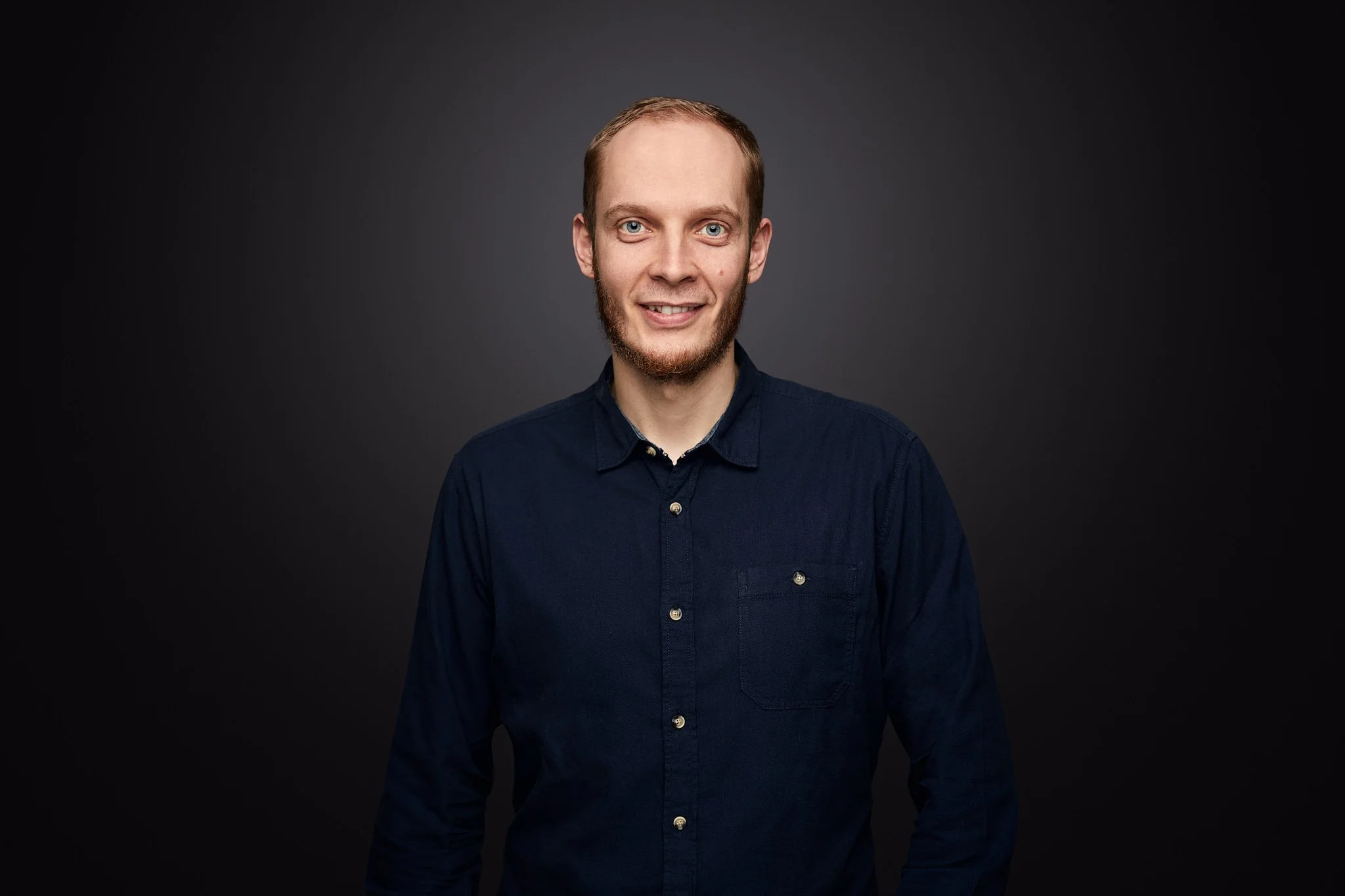 Fischbach Fenster Gründer und Geschäftsführer Felix Bertram, trägt eine dunkle Hemd, vor dunklem Hintergrund.