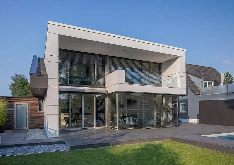 Modernes zweistöckiges Haus mit großen Fenstern und Außenjalousien.