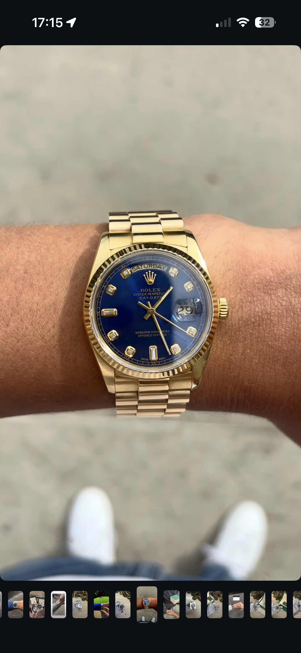 A man's wrist wearing a gold Rolex watch with a blue dial, gold hour markers, and a gold bracelet.