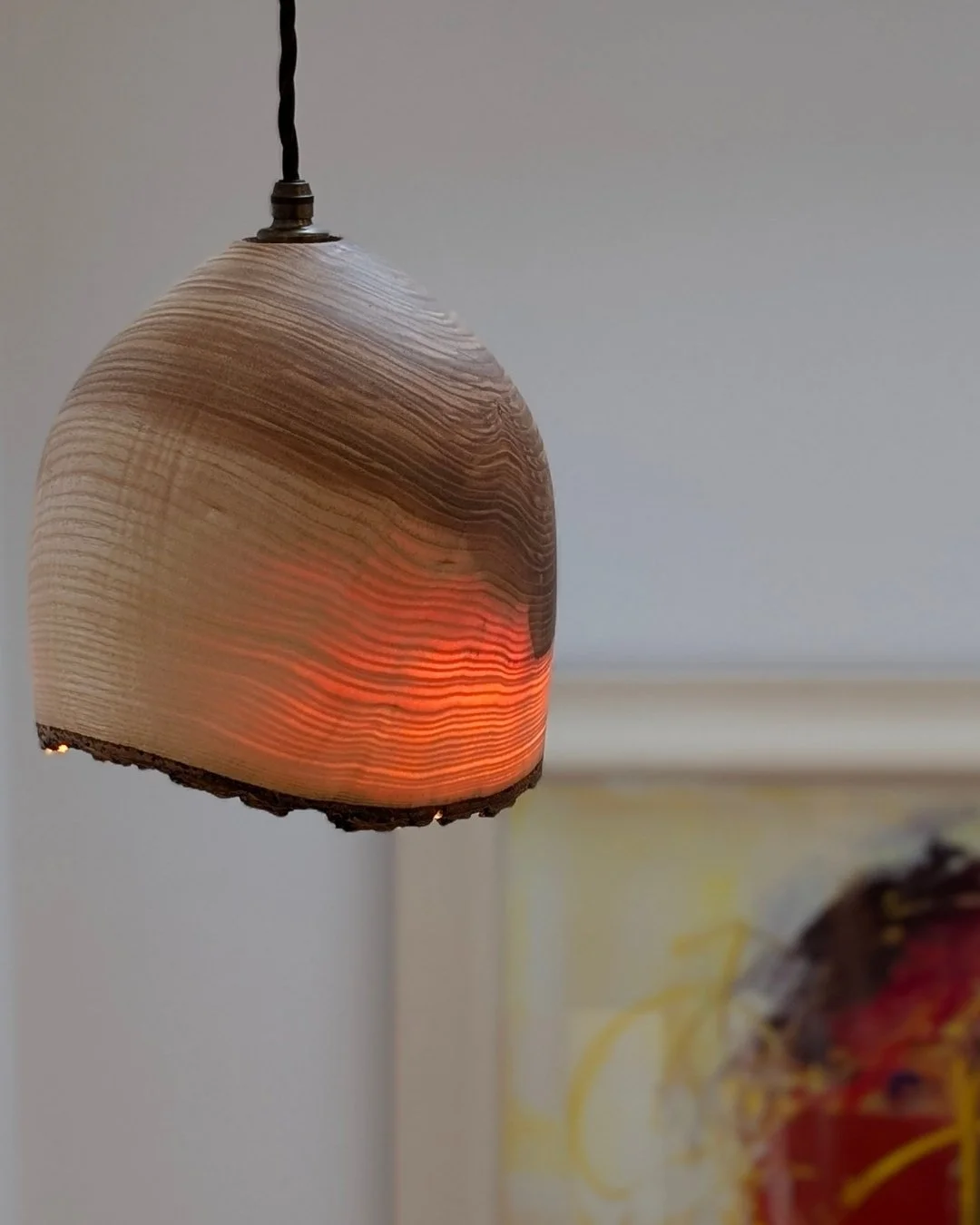 A wooden pendant lamp with a glowing light inside, hanging from a ceiling.