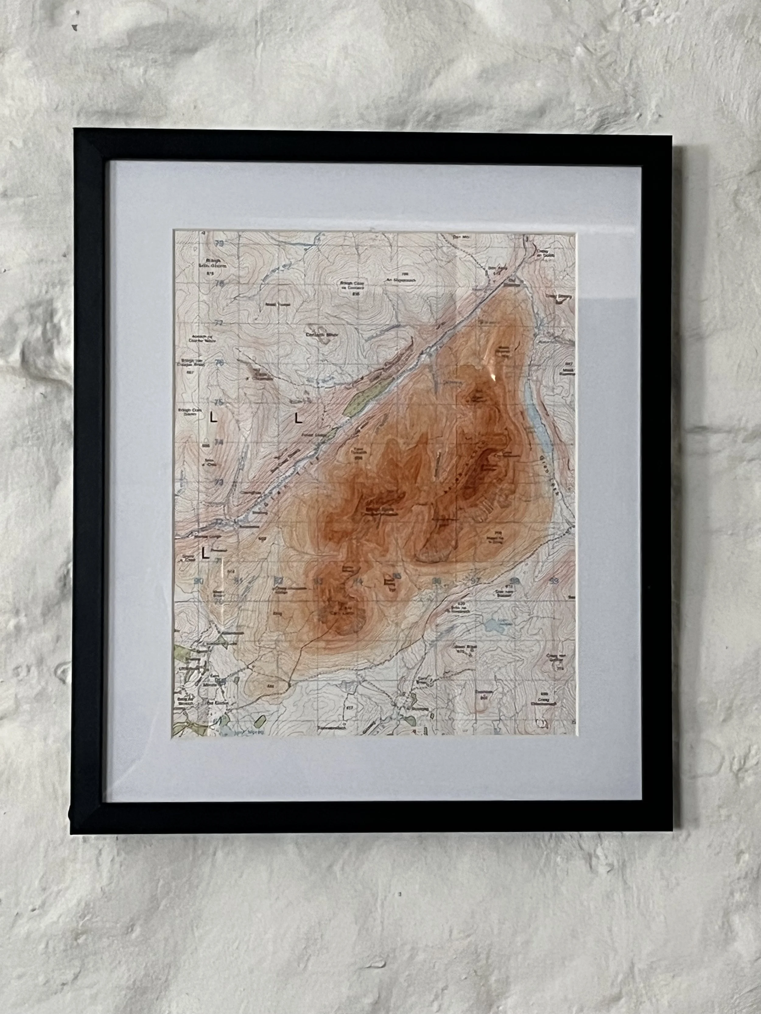 Framed topographic map hanging on a white wall.