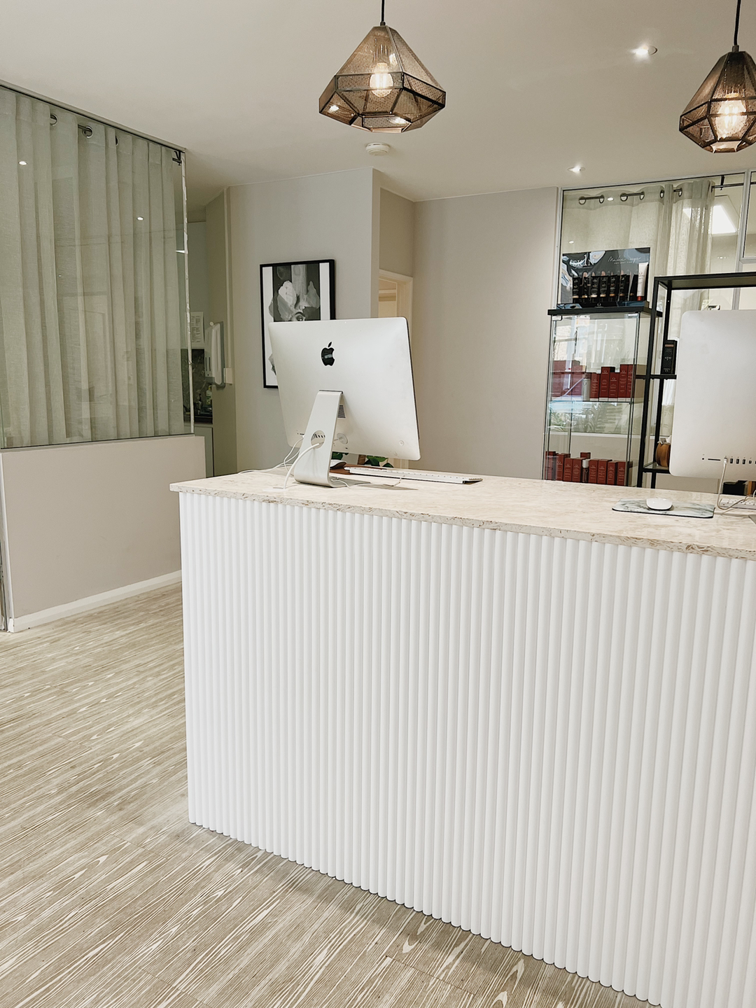 Modern reception desk with two iMac computers in a sleek, well-lit office or lobby space.
