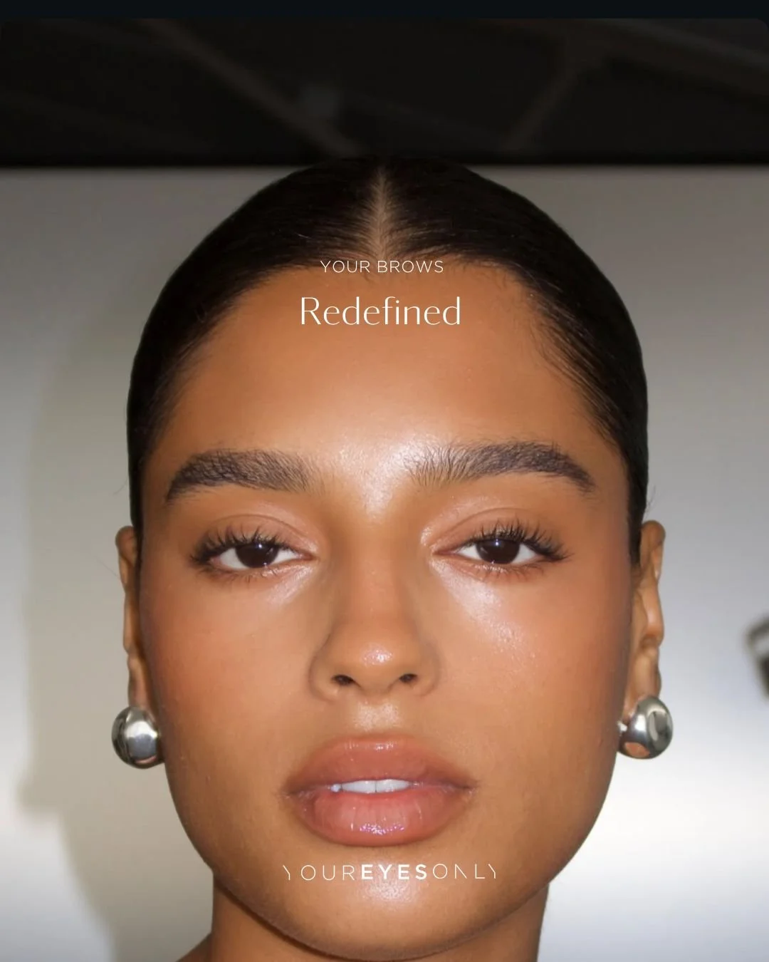 Close-up of a woman with well-groomed eyebrows and natural makeup, with text overlay about redefining eyebrows.
