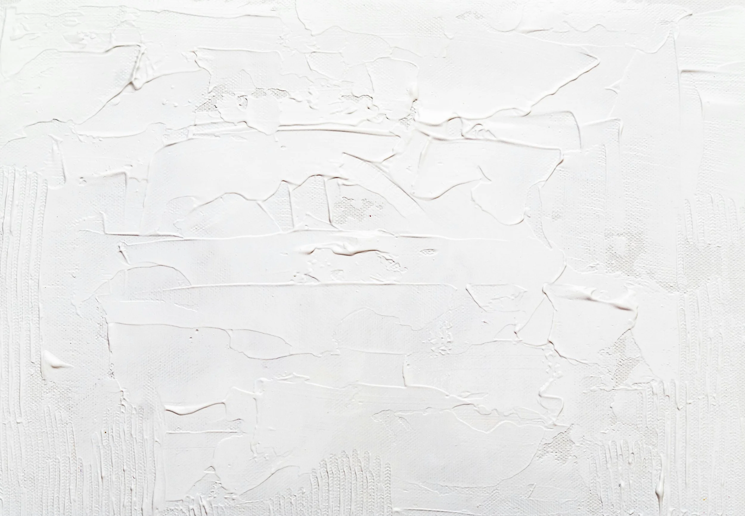 Close-up of a white textured surface with uneven, cracked, and layered paint or plaster.