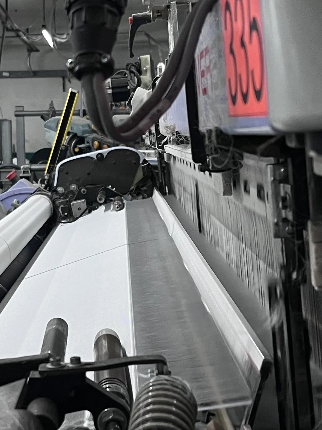 Proceso de tejido plano de acetato en telar itema mostrando la formación de tela para aplicaciones médicas con control de tensión y uniformidad