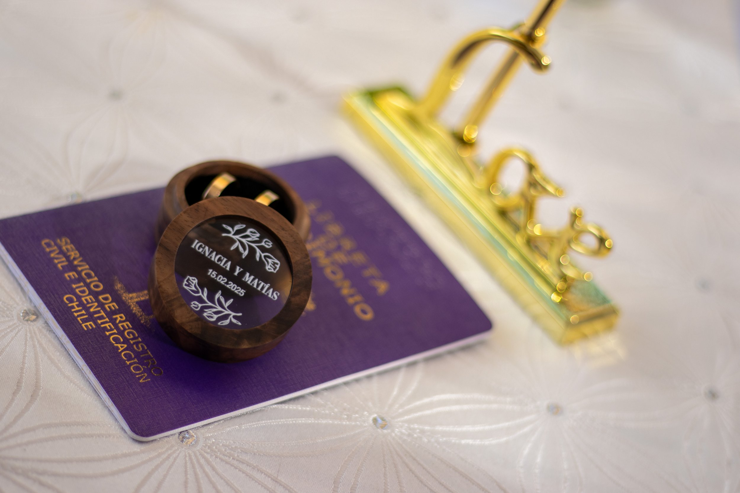 Anete de registro civil con una placa decorativa de anillo con nombres y fecha, y una litografía dorada.