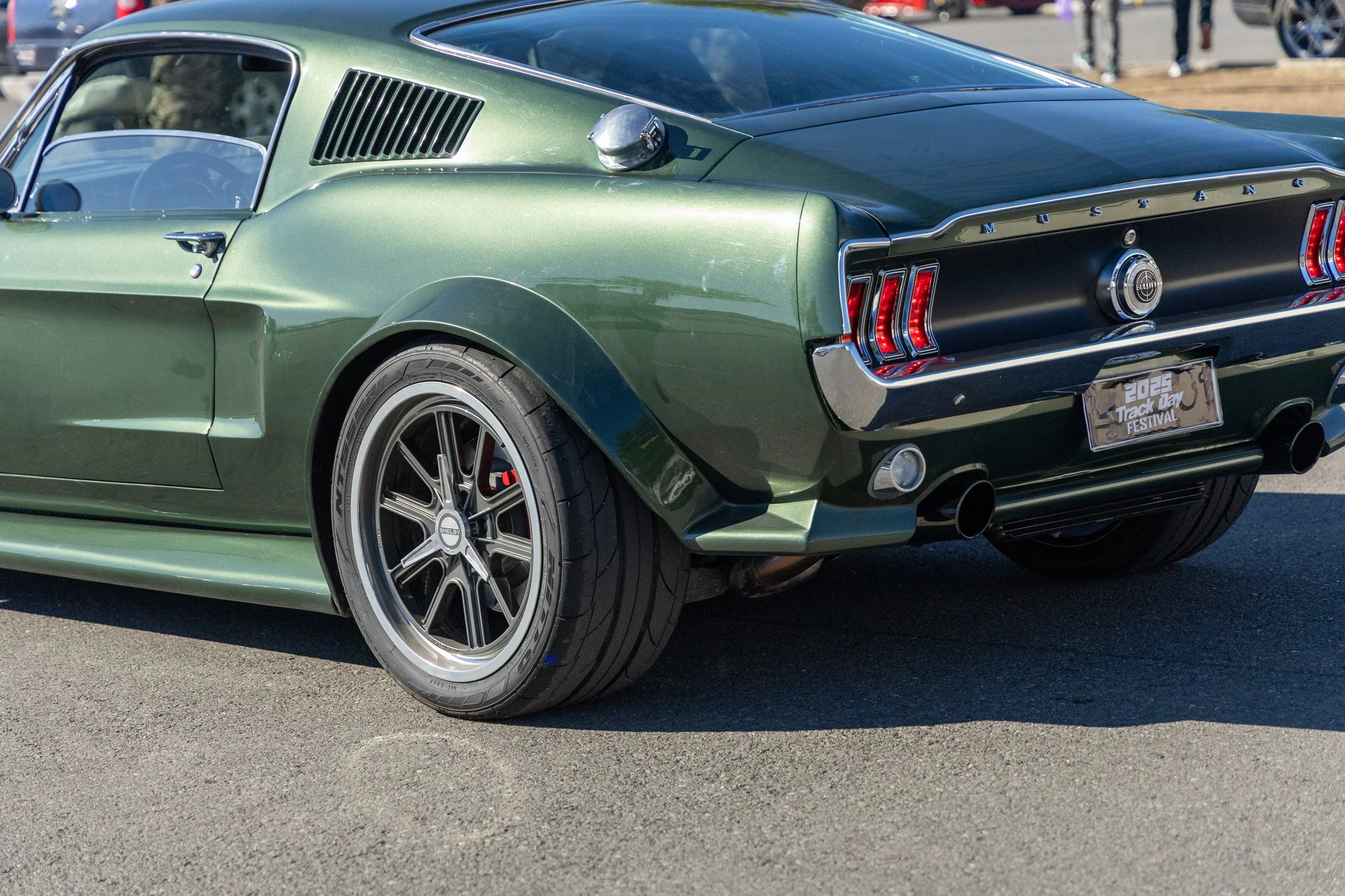 Auto clásico Ford Mustang verde con llantas deportivas en un estacionamiento.