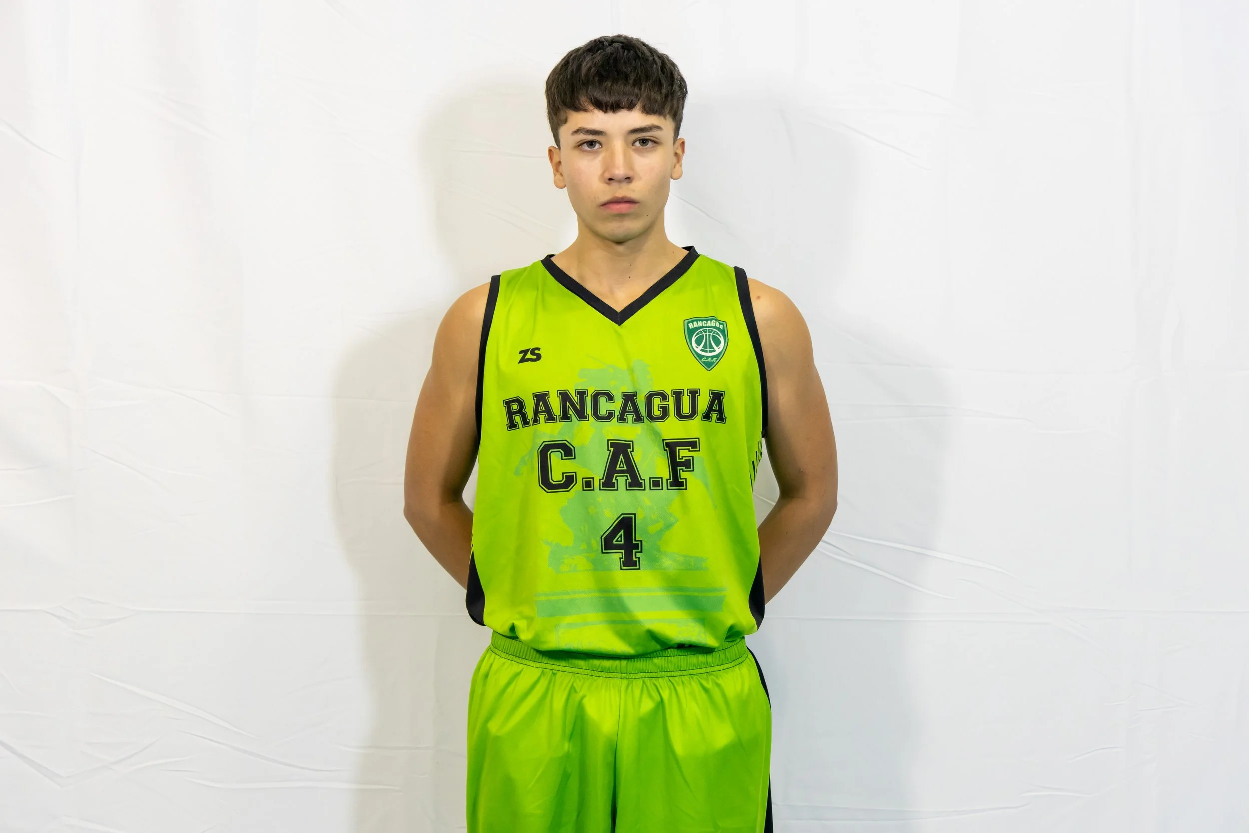 Joven deportista con uniforme de baloncesto verde con el logo de Rancagua C.A.F en un fondo blanco.