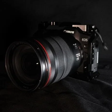Cámara réflex Canon EOS con lente grande, en un fondo oscuro.