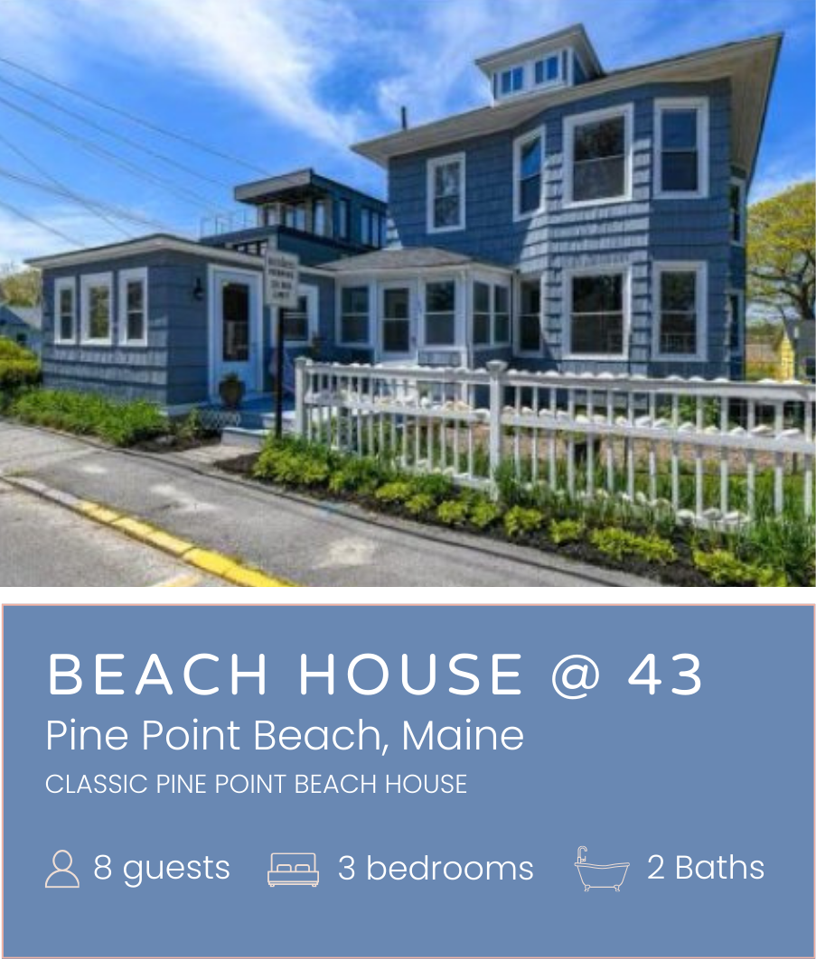 A large blue beach house with multiple levels and an angled roof, surrounded by a white fence and located along a street in Pine Point Beach, Maine.