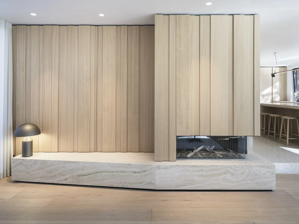 Moderner Kamin mit Holzverkleidung und Beleuchtung in hellem Holzdesign, auf einem Steinboden