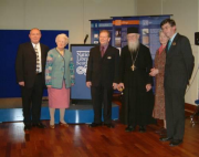 Group of five people dressed in formal attire standing on a wooden floor with blue display panels in the background. The Moir Library, Edinburgh.
