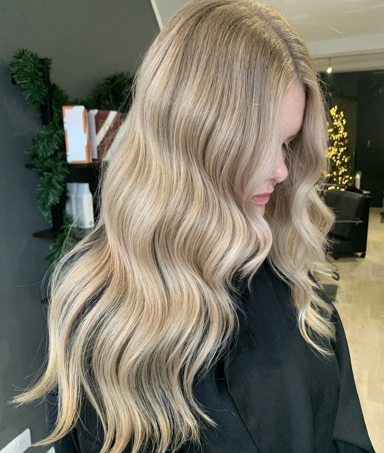 Side profile of a woman with long, wavy blonde hair in a salon.
