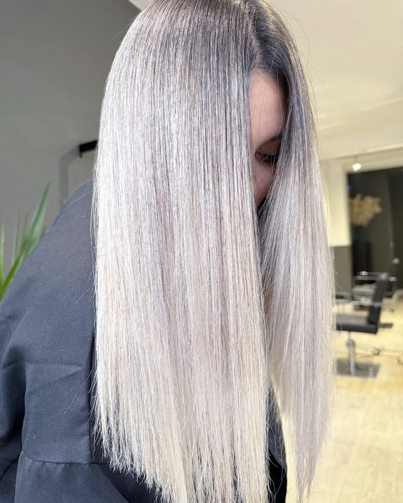 A person with long, straight, silver-blonde hair in a salon setting.