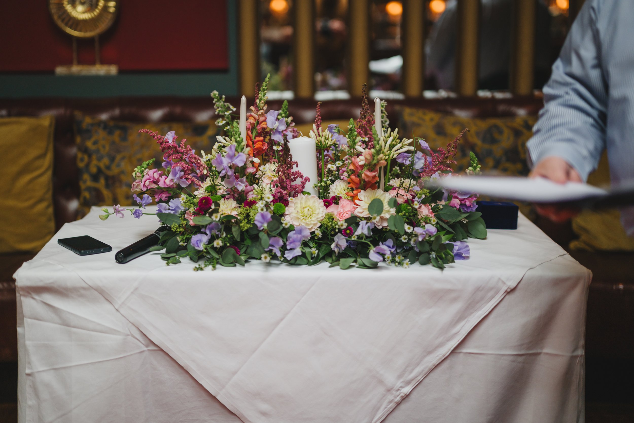 A floral arrangement with candles on a table, set in a cozy, decorated room.