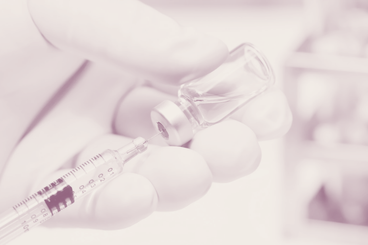 Closeup of a syringe drawing medication from a bottle