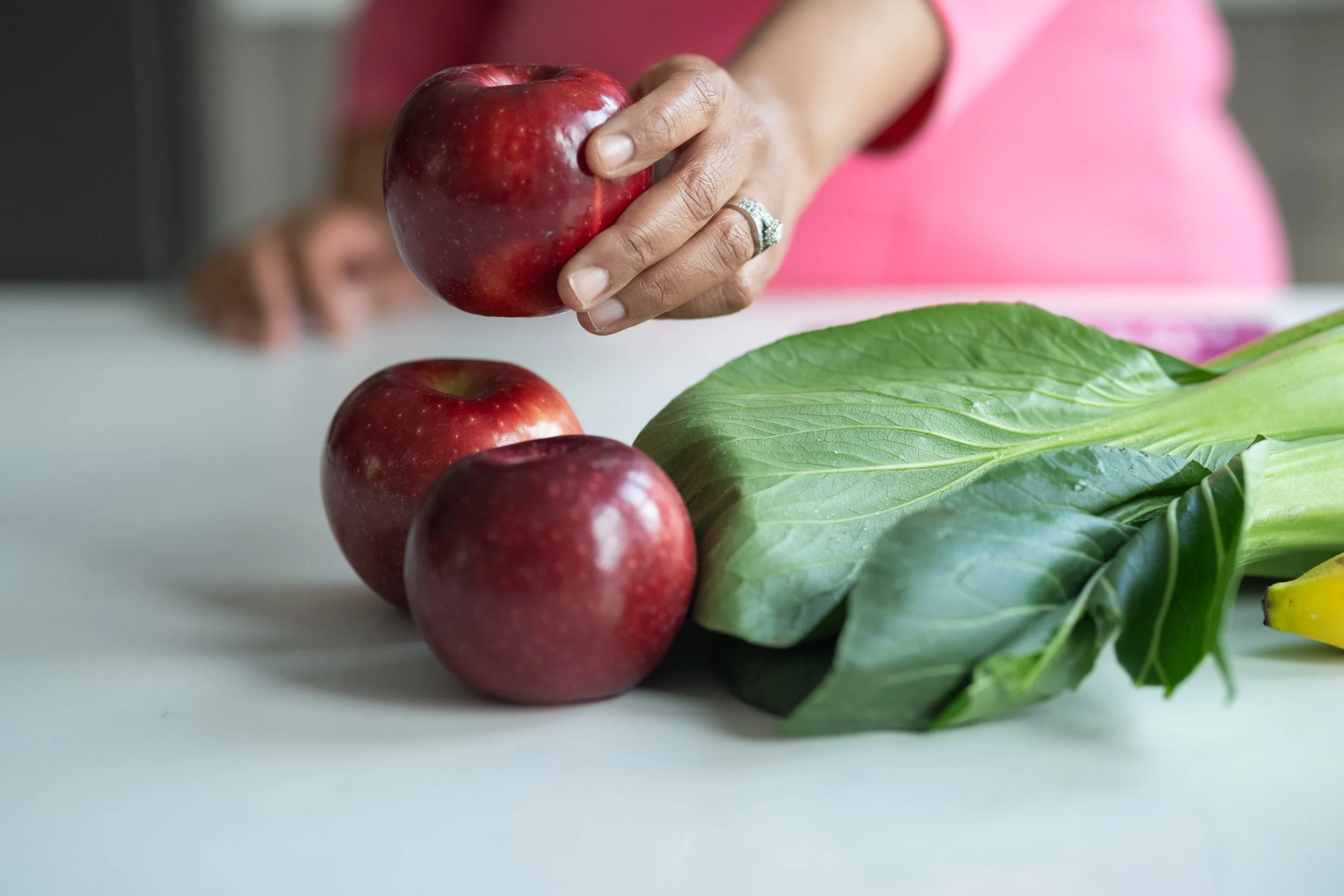 Three red delicious apples with a bunch of bok choy