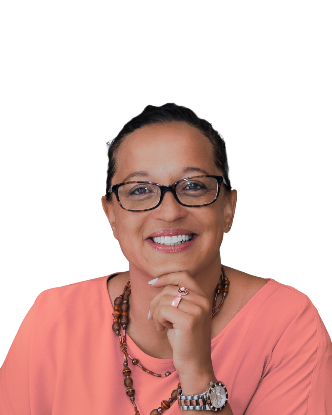 A smiling woman with glasses, short dark hair, wearing a peach-colored top, a beaded necklace, a watch, and a ring, resting her chin on her hand.