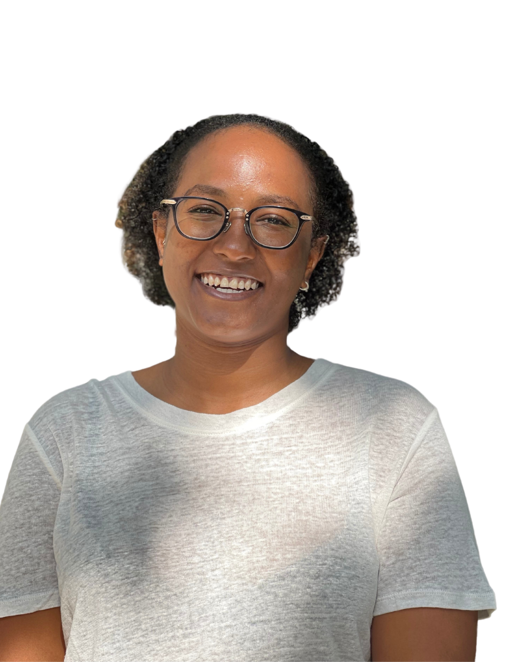 A woman with short curly hair and glasses smiling, wearing a light grey t-shirt.