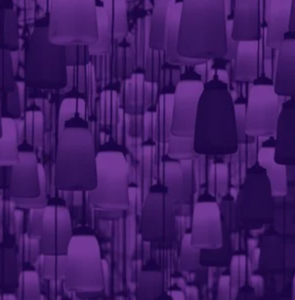 A chandelier made of multiple chairs hanging upside down, illuminated with purple lighting.