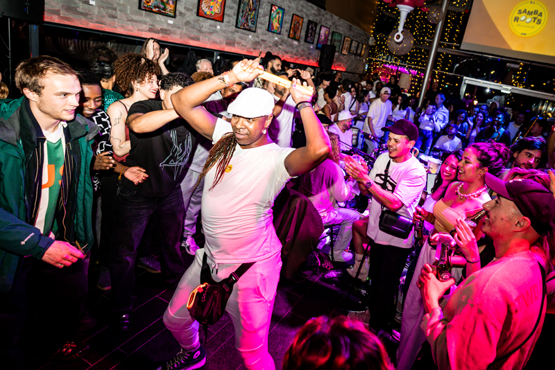 People dancing and enjoying music in a lively nightclub or party venue with colorful lights, wall art, and festive decorations.