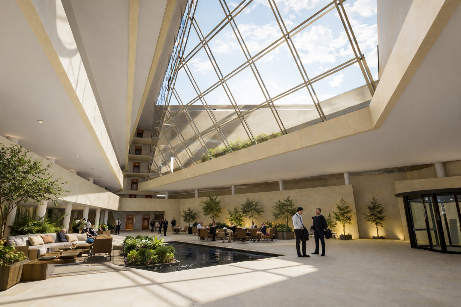 Le hall d'un bâtiment moderne avec un plafond en verre, un bassin d'eau avec des plantes, des fauteuils, des plantes en pot et des personnes discutant ou se reposant.