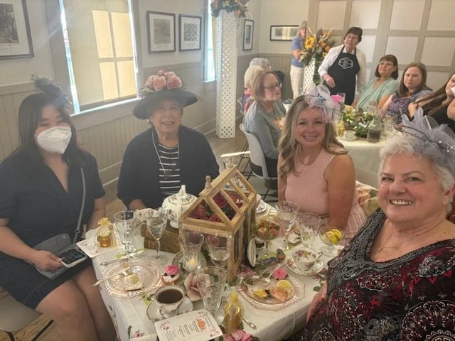 Four ladies sitting around a table enjoying food and tea
