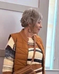 Female model wearing a rust colored vest over a striped sweater