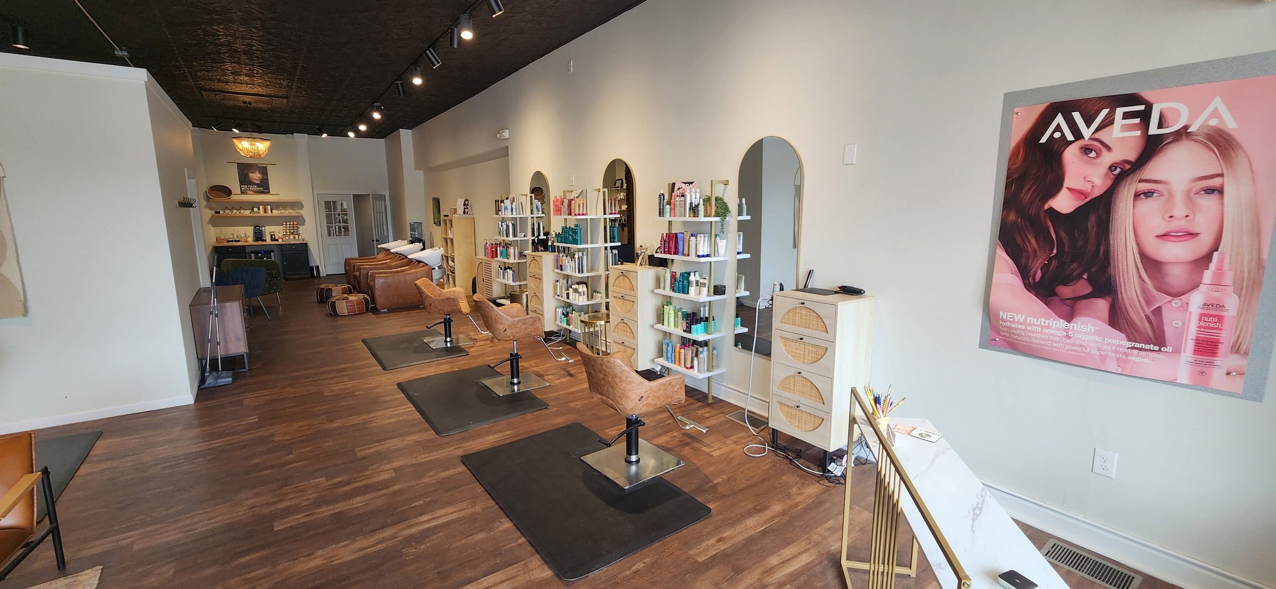 3 salon stations with a chair, styling cart,  mirror, and products at each station