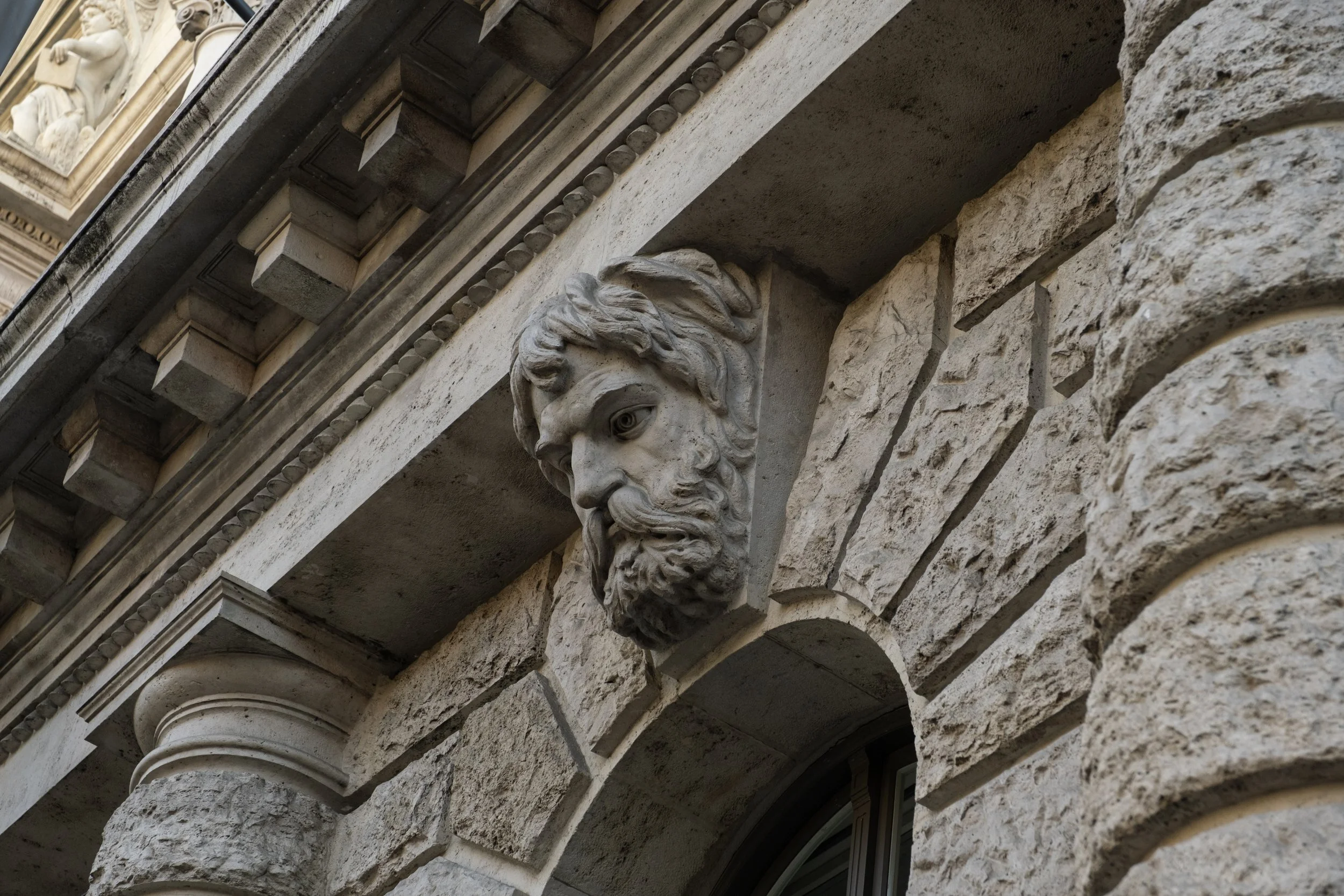 Close-up of ornate architectural details on a historic building, including a carved stone lion's head and decorative elements on the facade.