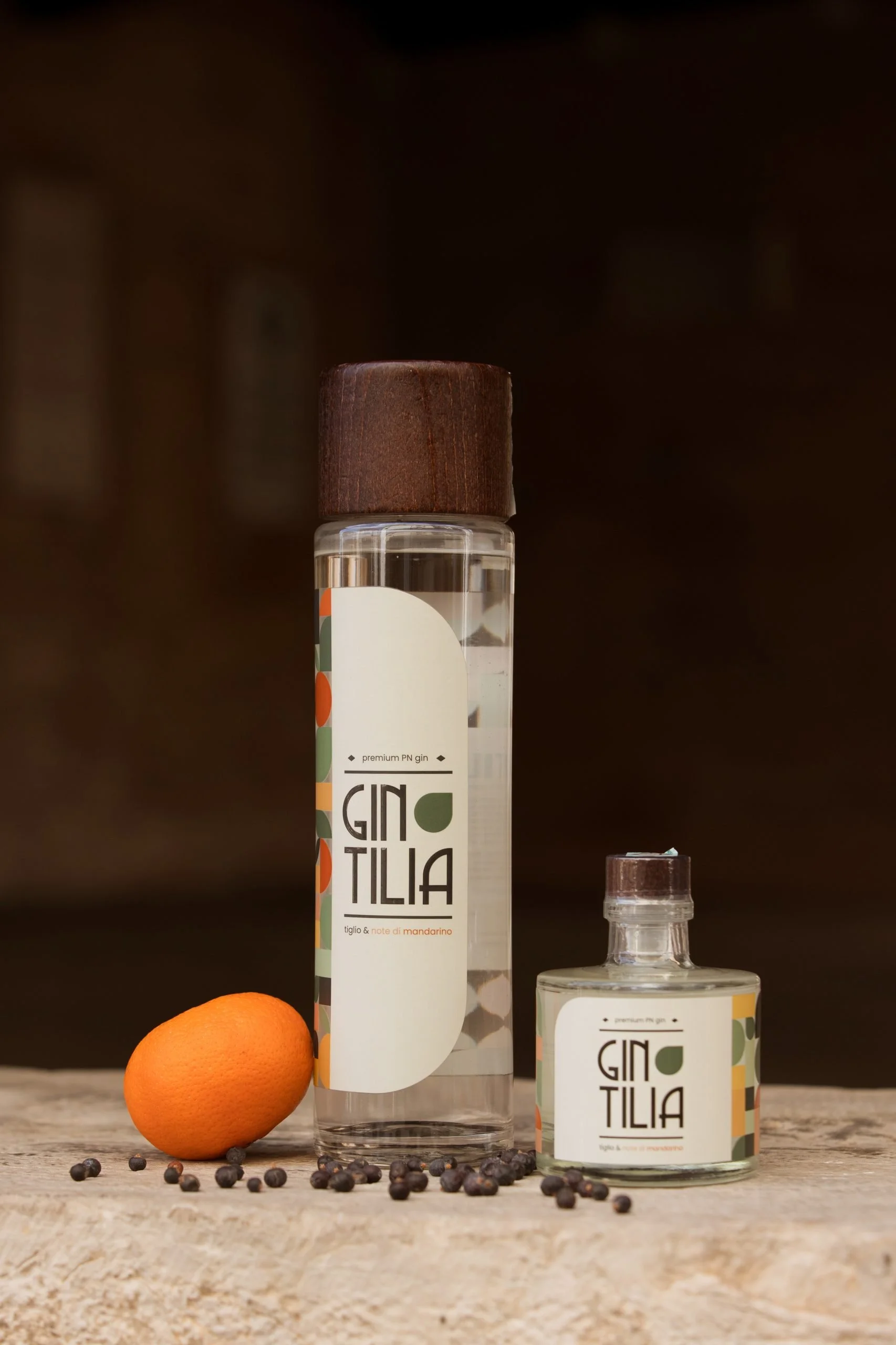Bottle di gin Tilia con un'orange e bacche di pepe nero su un tavolo di legno