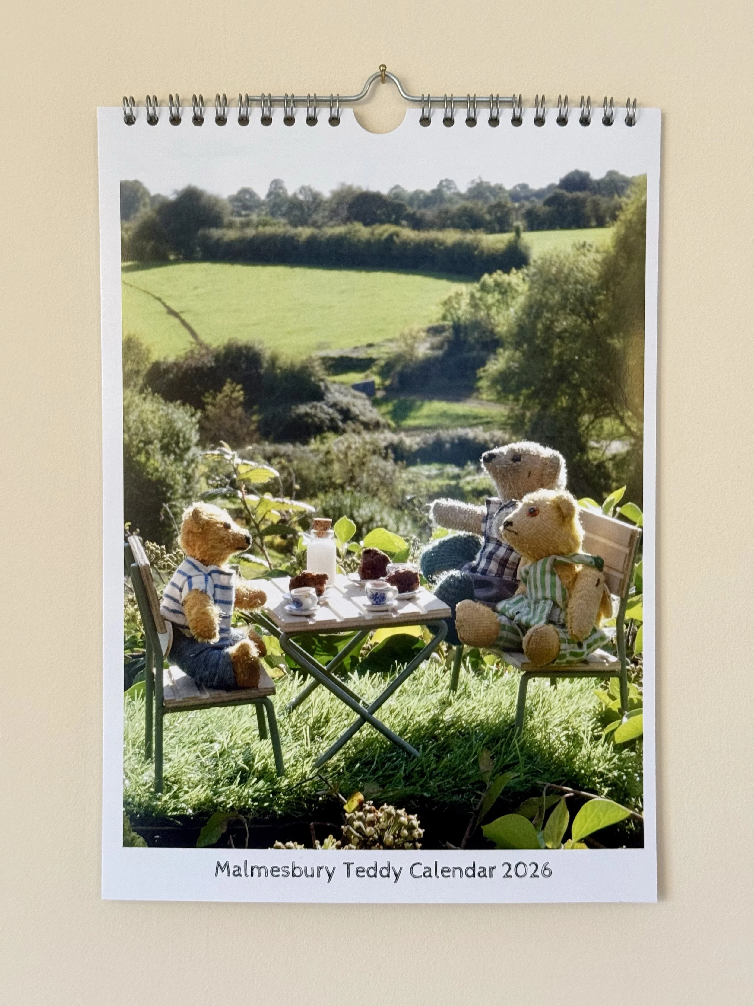 Cover of the Malmesbury Teddy Calendar 2026 featuring teddy bears having tea outdoors with a lush green landscape in the background.