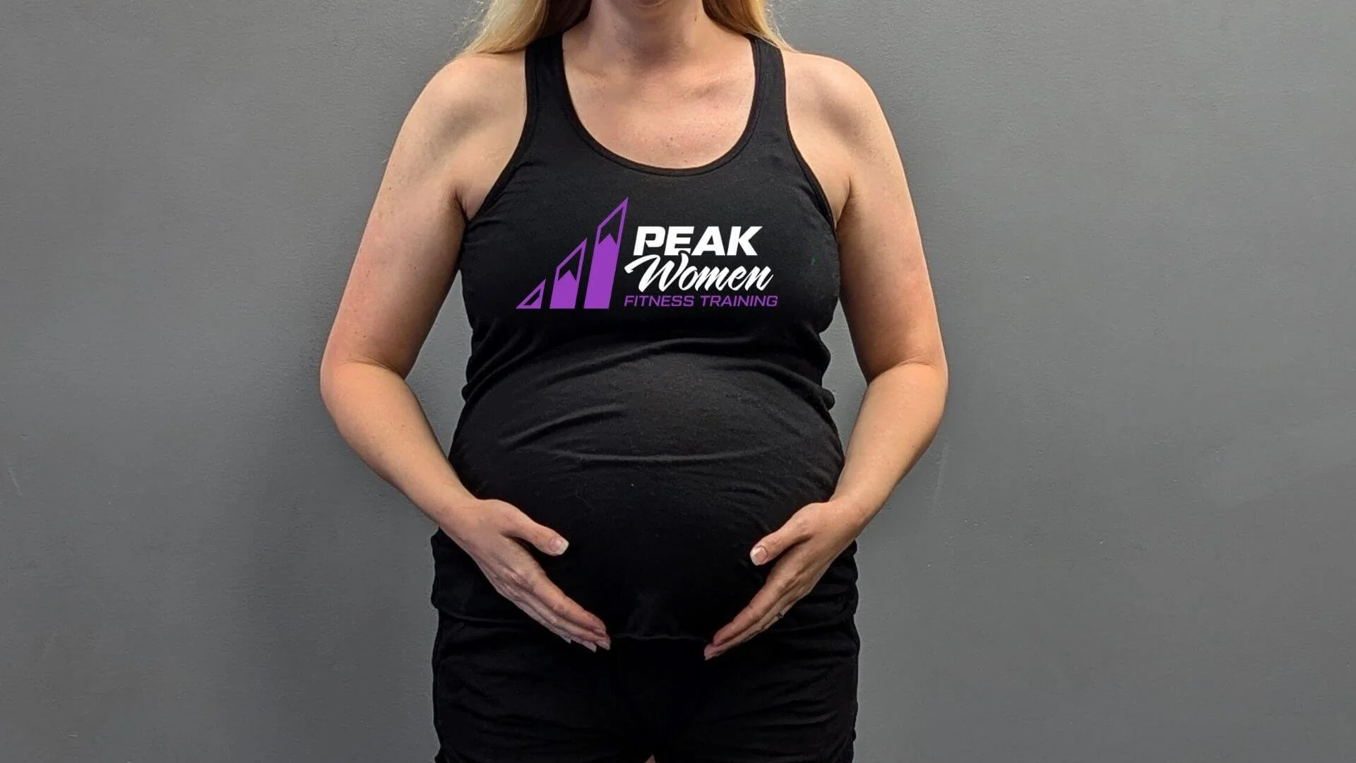 pregnant woman holding her belly in workout gear