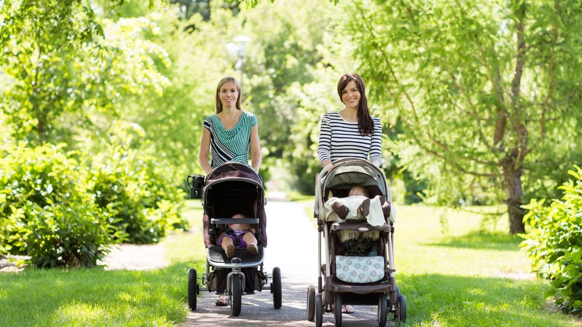 two women walking their babies in strollers