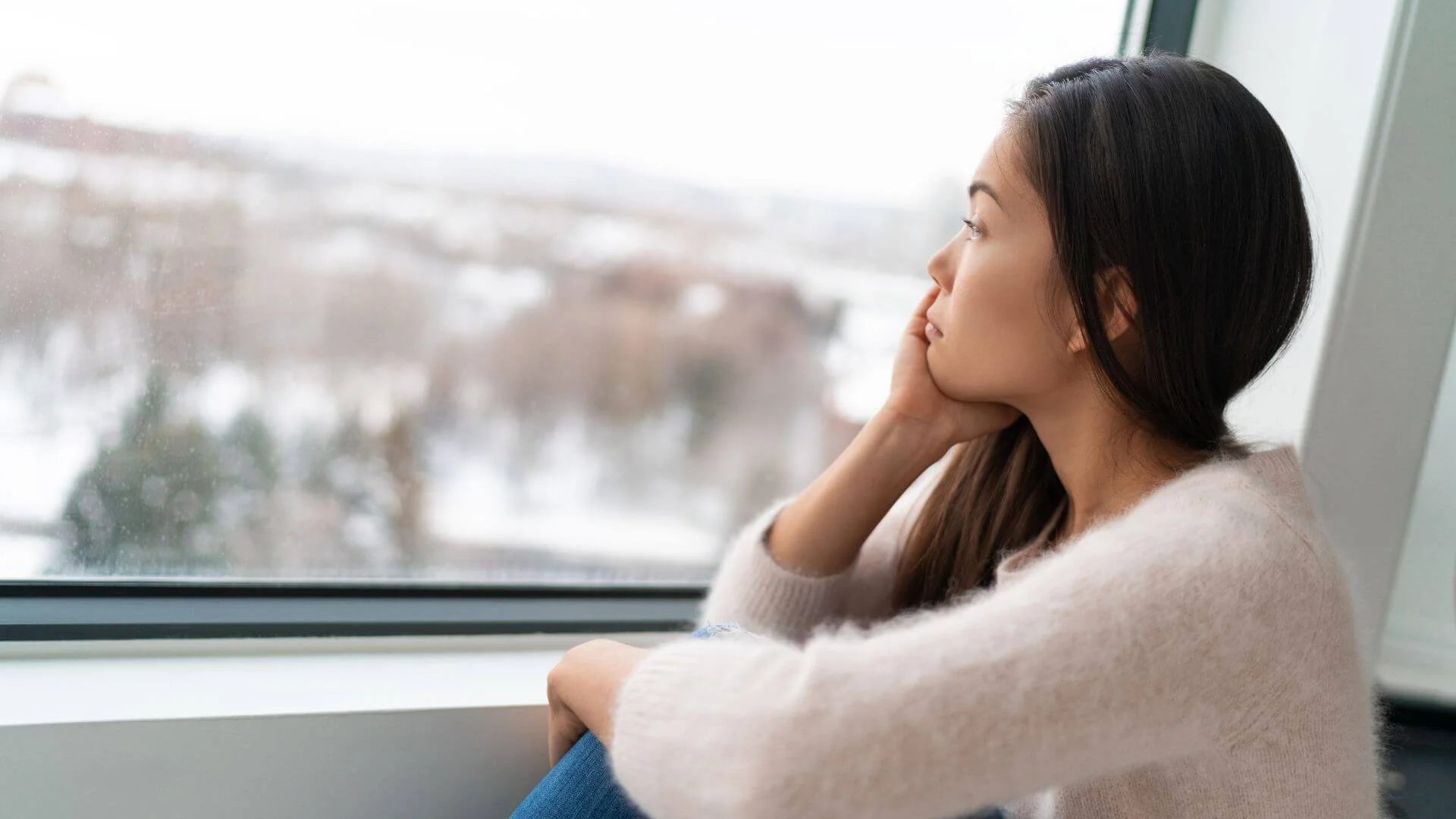 woman looking sad looking at the snowy weather