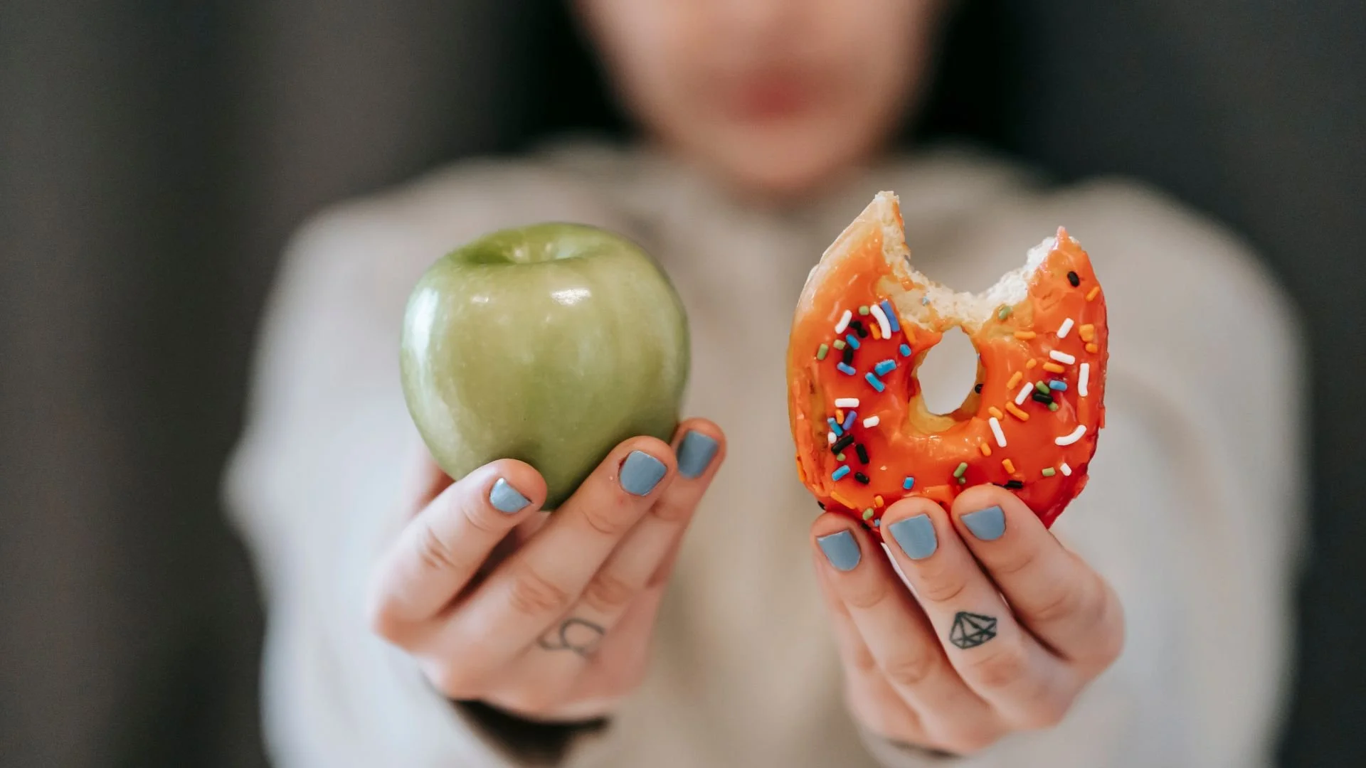 woman holding up an apple and donut