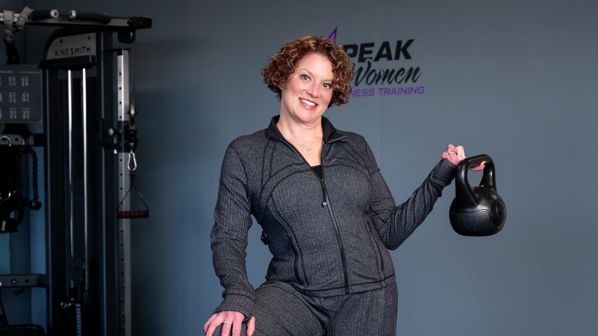 Lissa, owner of Peak Women, holding a weight in her women only gym in troy michigan