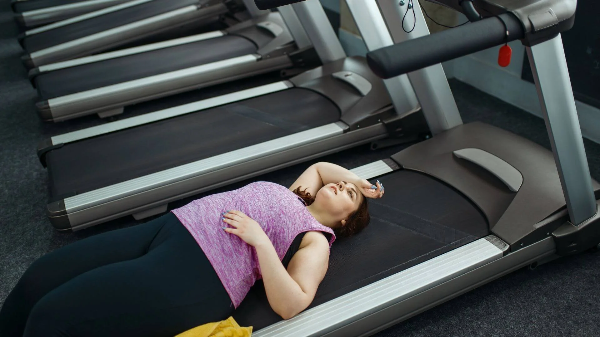 a woman laying on a treadmill with no motivation to exercise