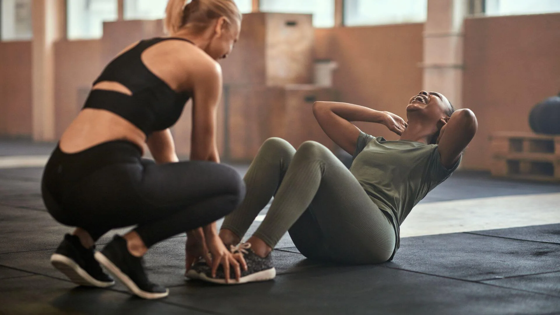 woman laughing while exercising with her female personal trainer