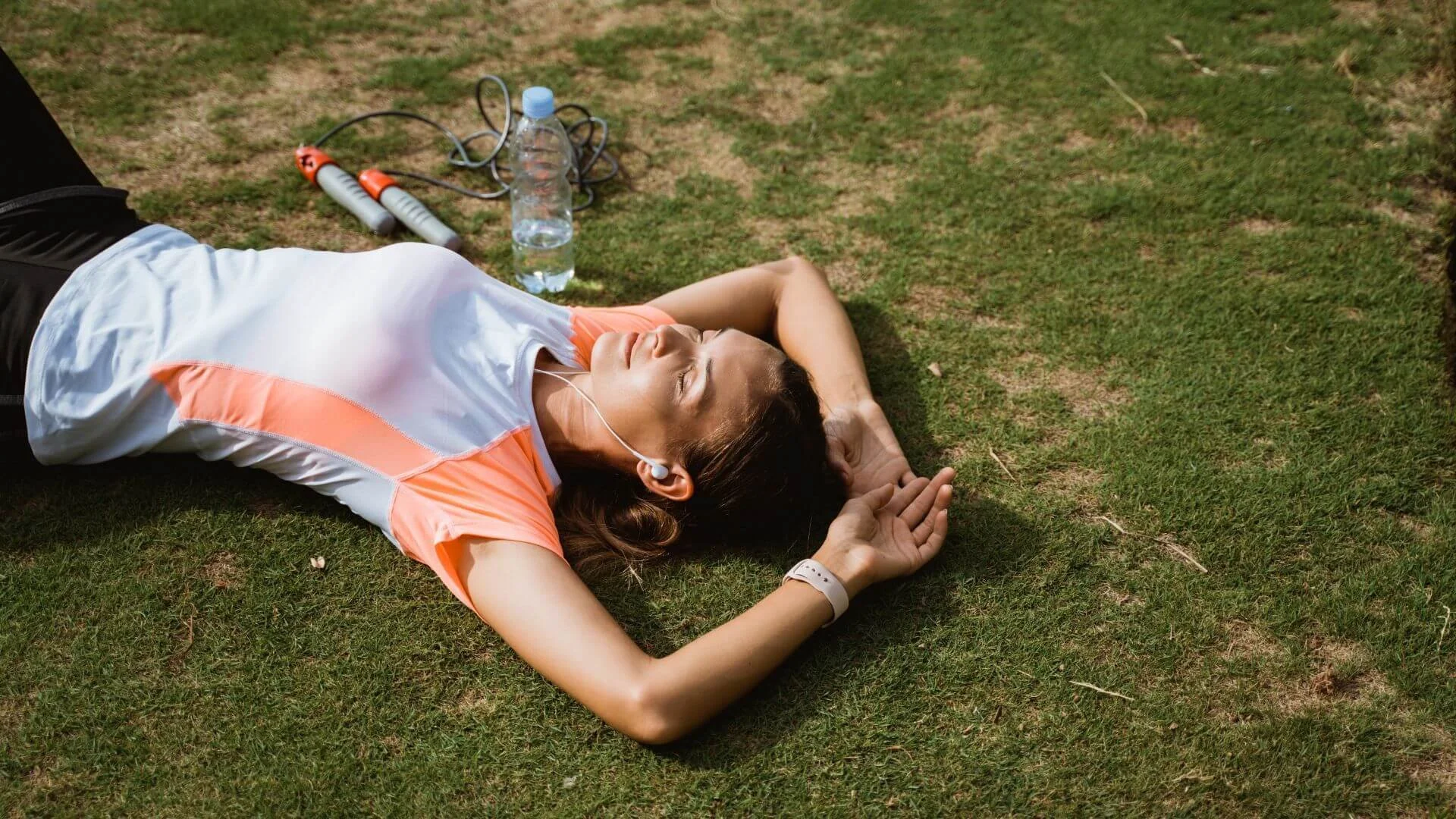 woman laying down in the grass exhausted after running