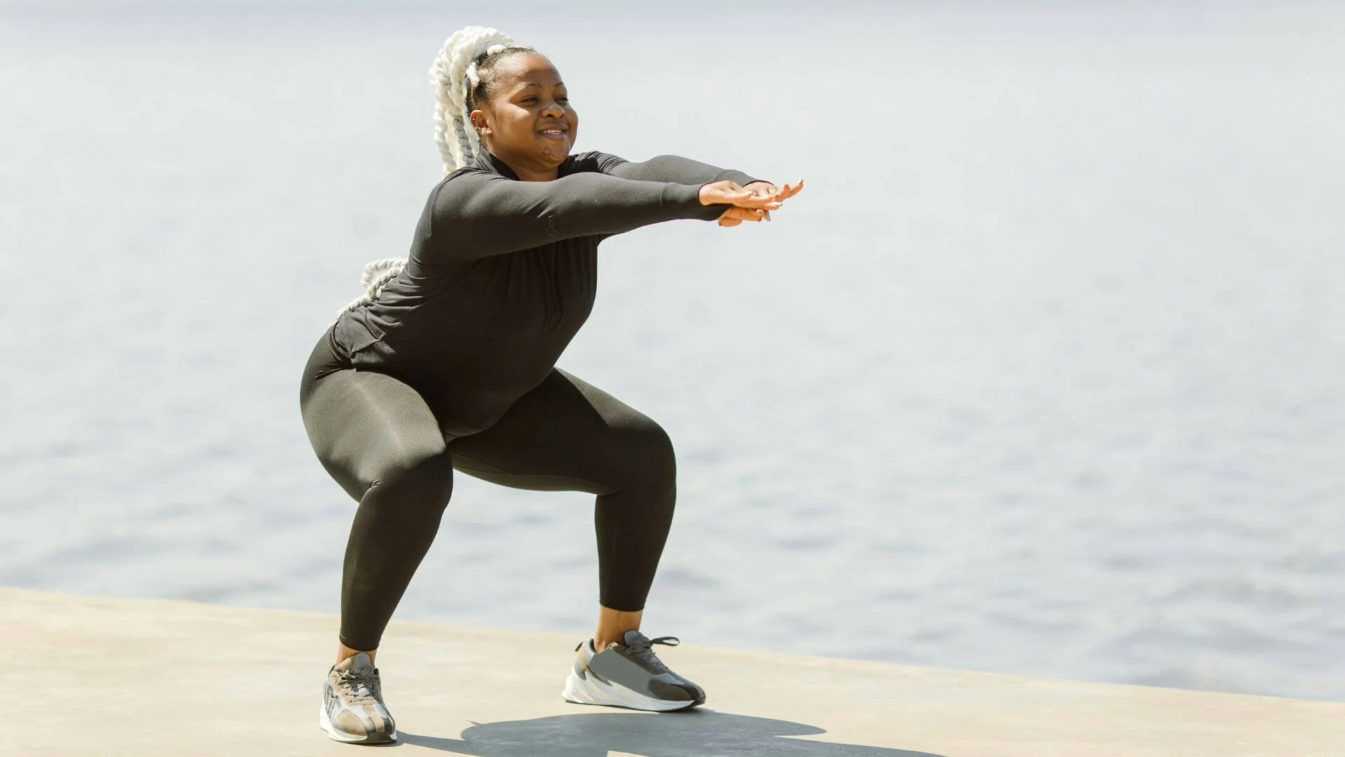 woman doing squats near the water