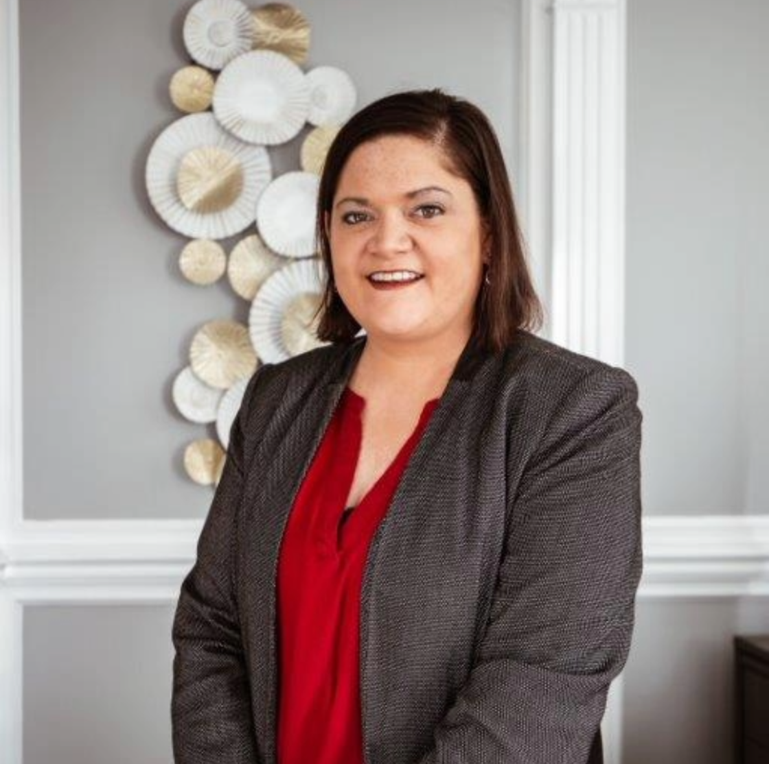 A black and white curly-haired dog with its mouth open and tongue out, in an indoor setting.