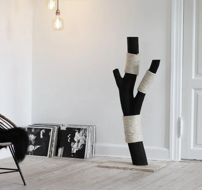 Skulpturelt designmøbel til katte i træ og natur-sisal, placeret i et lyst boligmiljø