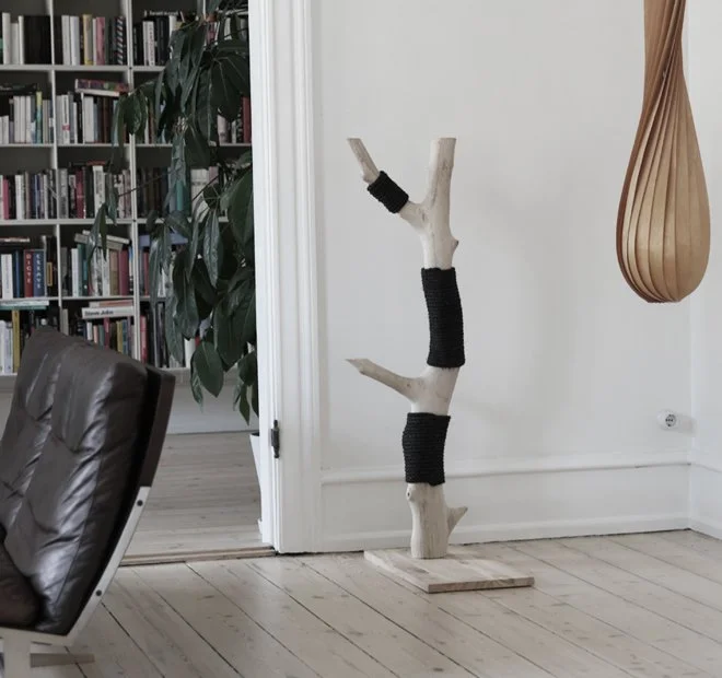 Lyst kradsetræ til katte i masivt træ og sort natur-sisal ved siden af lampe