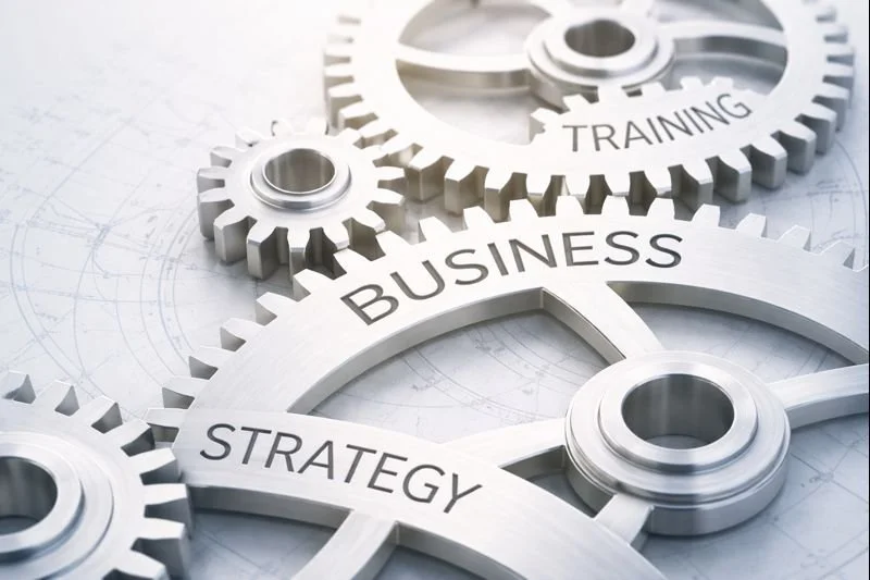 Silver gears with words 'Business,' 'Strategy,' and 'Training' on them, symbolizing interconnected business processes.