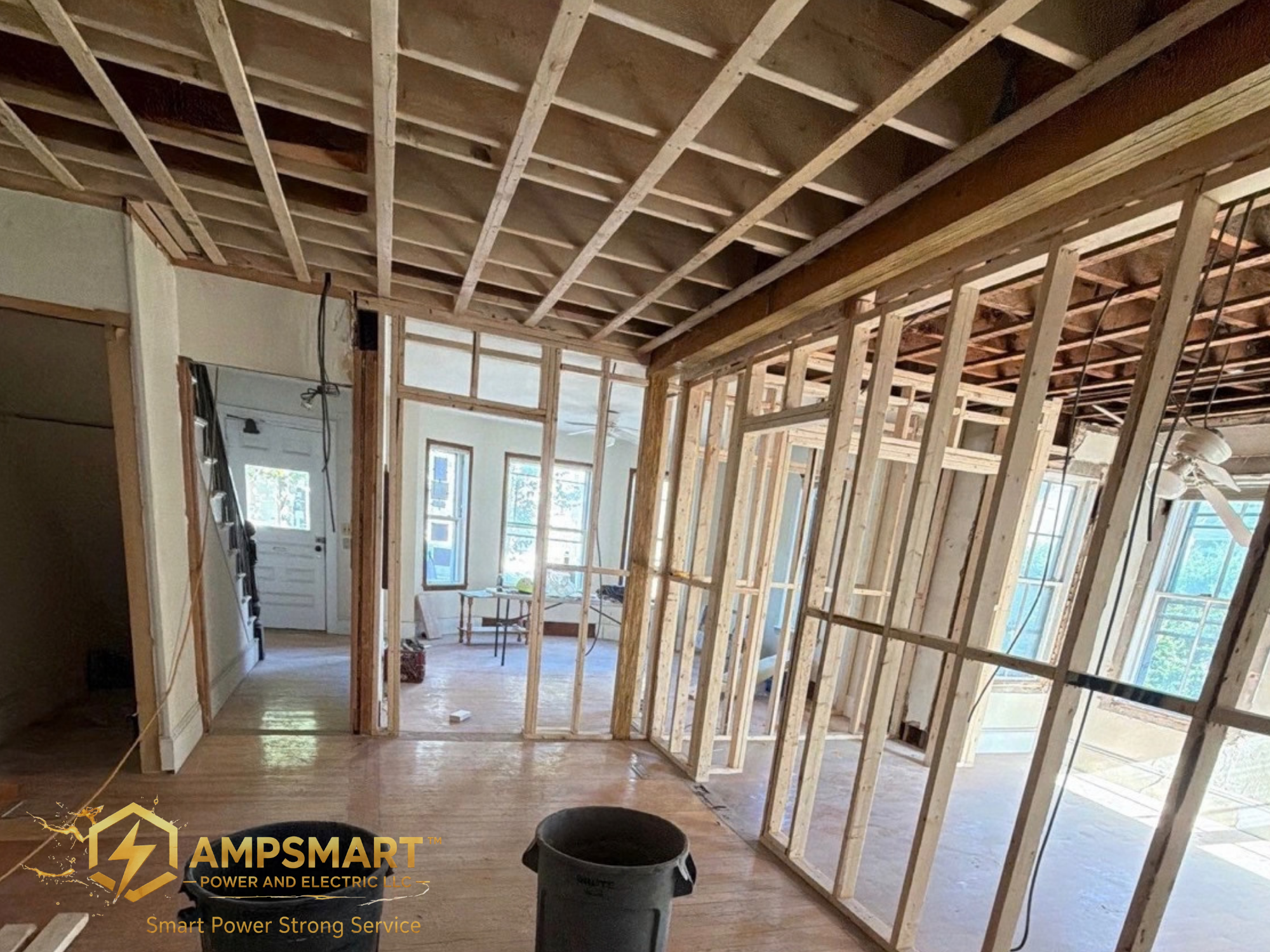 Interior of a house under construction, showing exposed wooden framing, ceiling joists, and window frames.