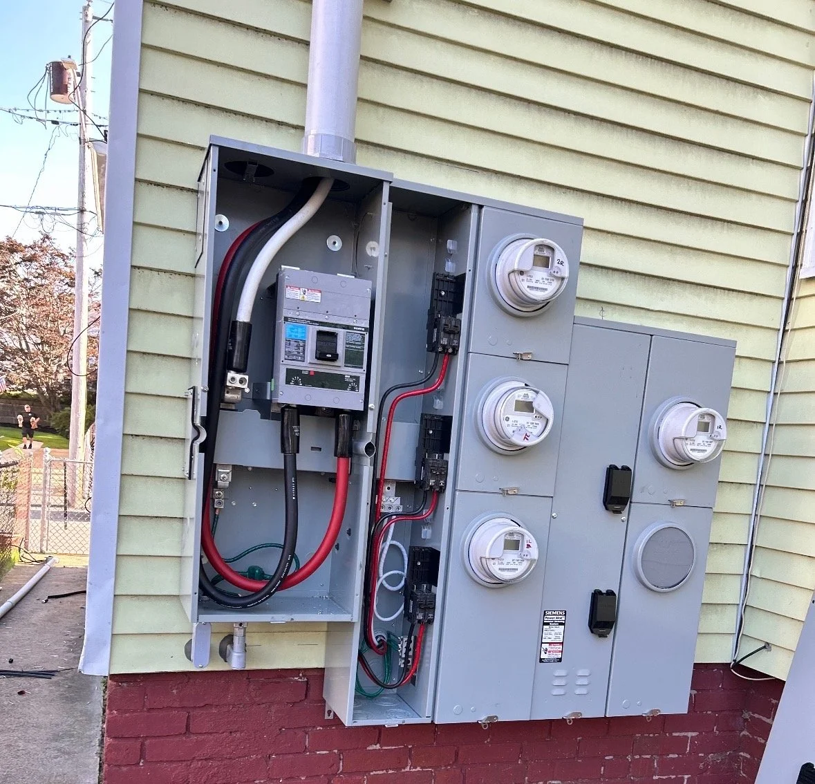 Electrical meter box attached to the exterior of a house, containing multiple meters and electrical components.