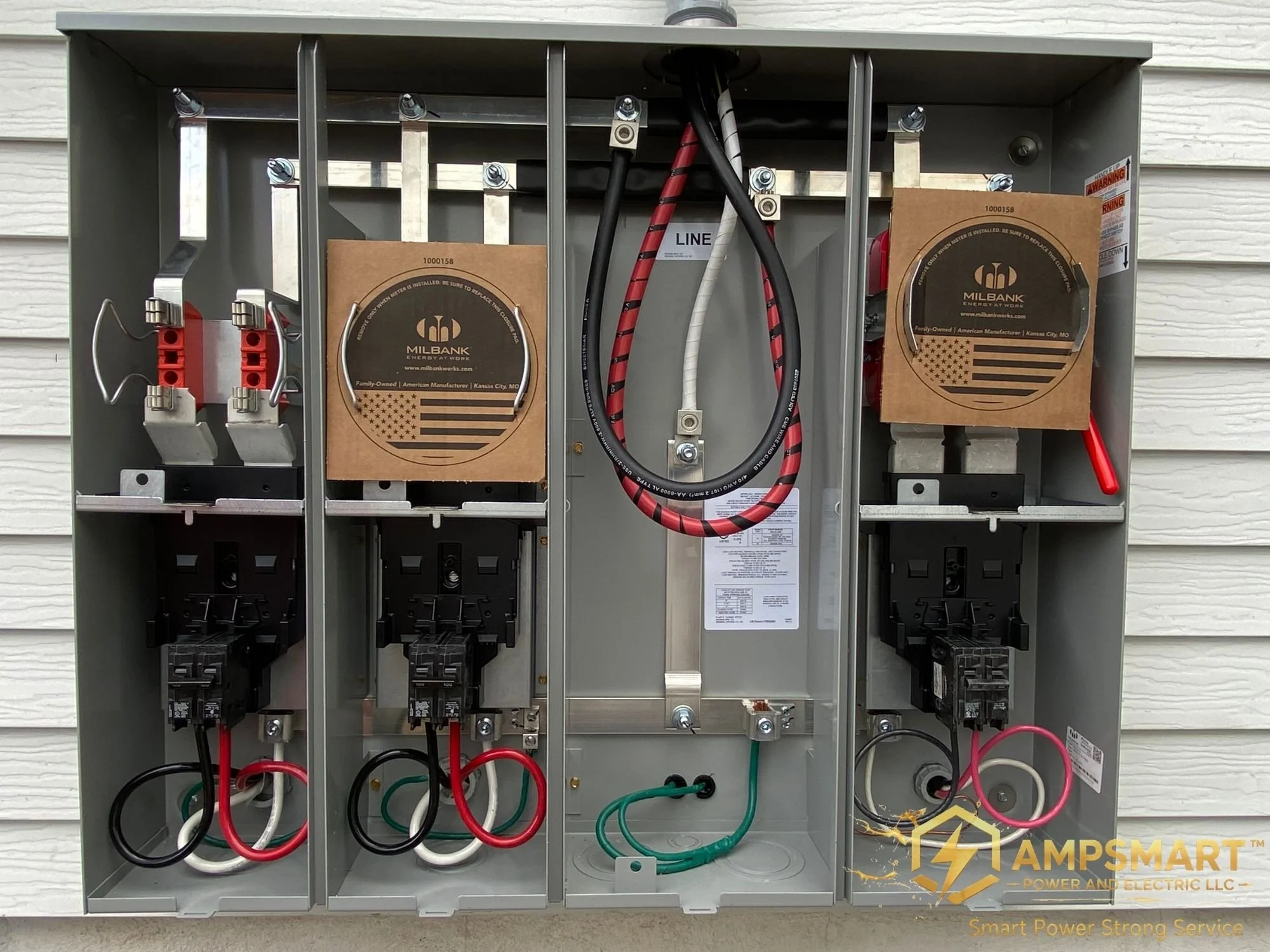 An electrical panel with various wires, circuit breakers, and components inside. The panel is mounted outdoors against a house wall.