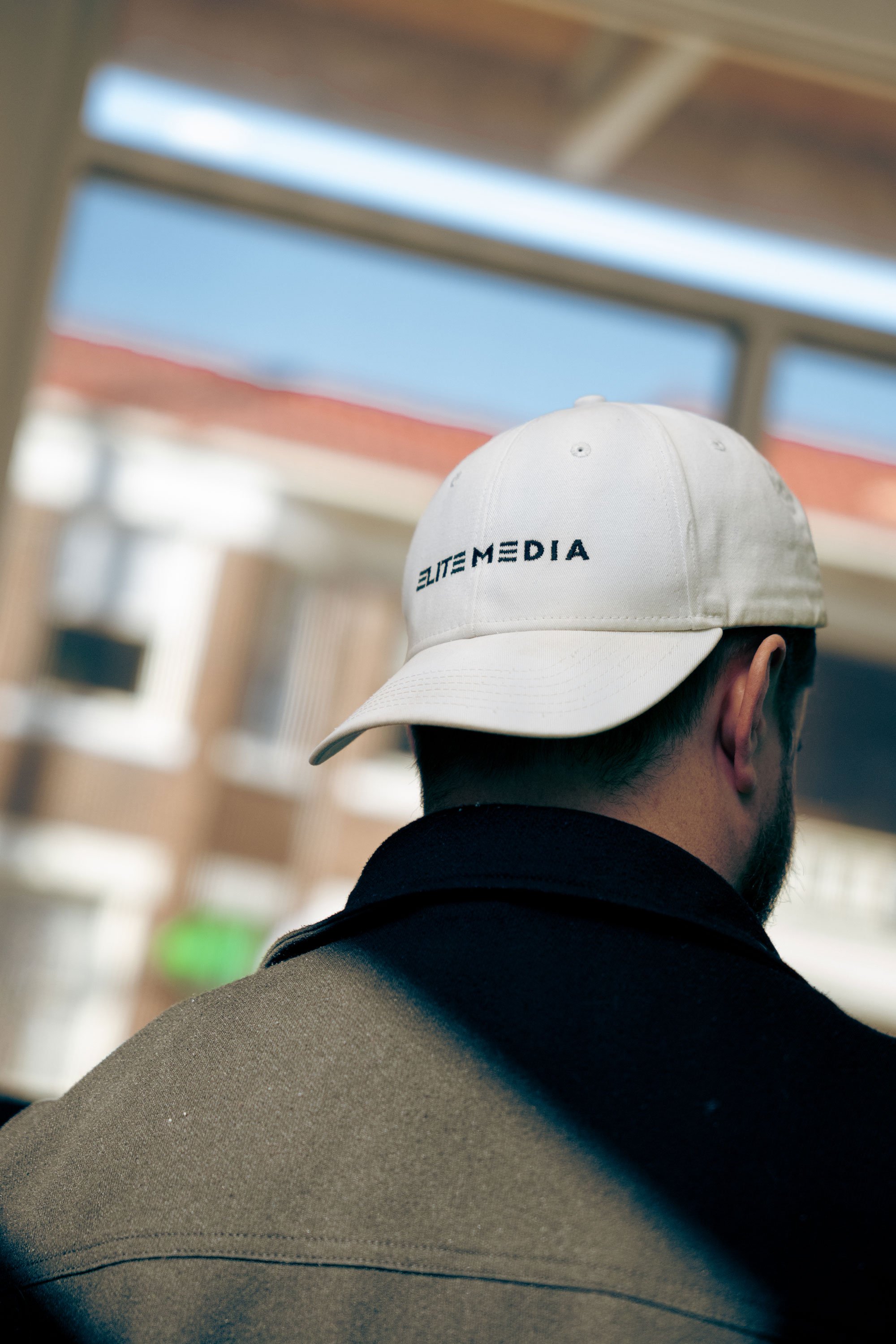 logo of elite media on a white hat